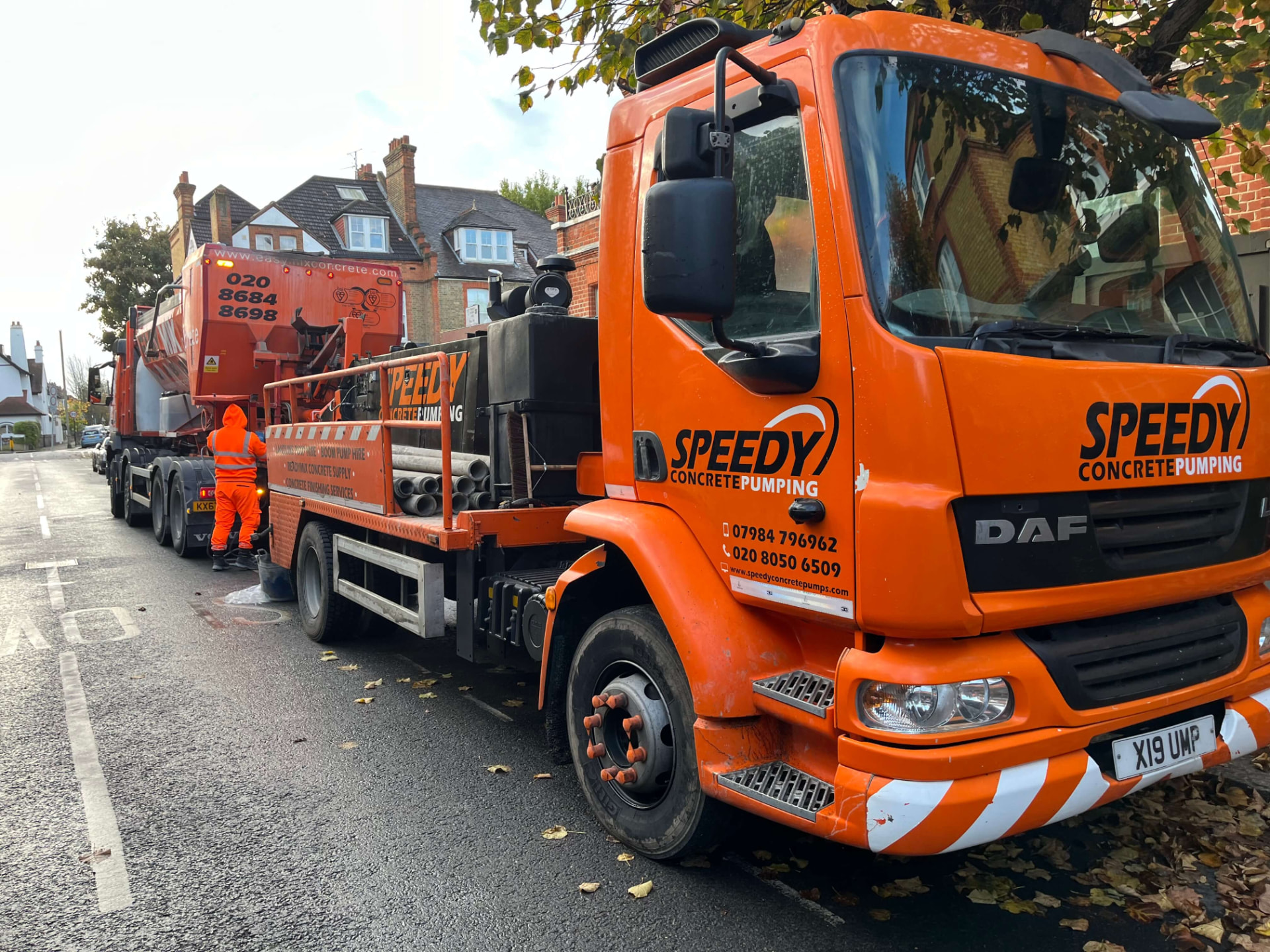 Orange Speedy Concrete Pumping readymix supply truck on a residential street